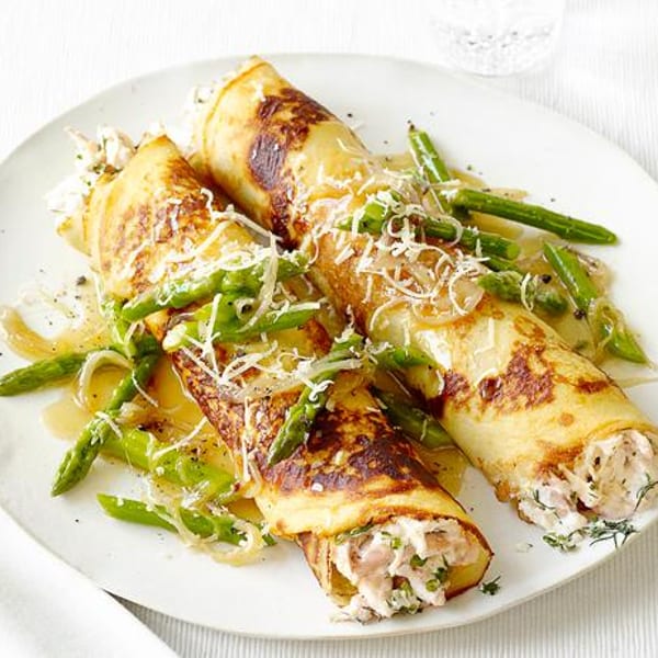 Two savory crepes filled with chicken and herbs, topped with asparagus, onions, and shredded cheese.